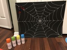 three spray paint bottles sitting on top of a wooden floor next to a spider web