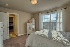 a bedroom with a bed, dresser and large window in it's center area