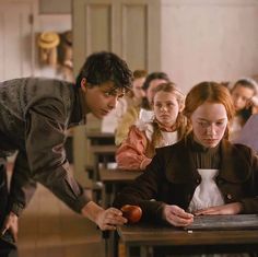 a group of people sitting at desks in a classroom with one person writing on a notebook