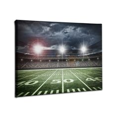 an american football field at night with the lights on and dark clouds in the sky