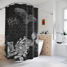 a black and white shower curtain with flowers on it in a bathroom next to a bathtub