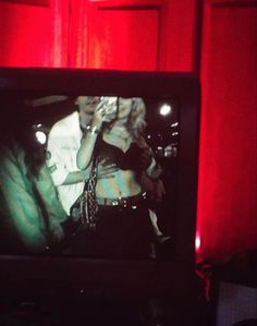 a television screen with a man and woman on it in front of a red curtain