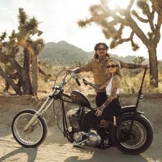 a man and woman on a motorcycle in the desert