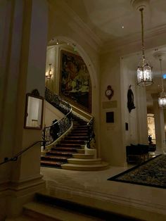 an elegant staircase with chandeliers and paintings on the walls