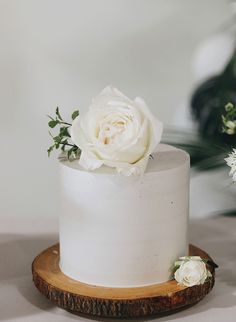 there is a white cake with flowers on the top and bottom, sitting on a wooden stand