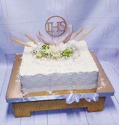 a square cake with white frosting and flowers on top, sitting on a table