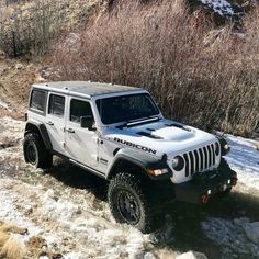 a white jeep is driving through some snow