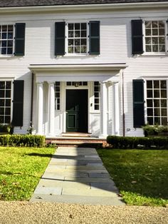 a large white house with black shutters on the front door and windows in the side