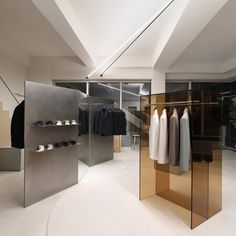 an empty clothing store with mirrored walls and clothes hanging on the racks in front of them