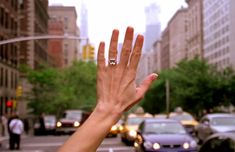 a person's hand with a ring on it in the middle of a city street