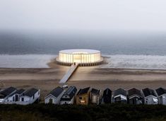 an aerial view of some houses by the beach and water at dusk with fog in the air