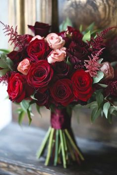 a bouquet of red and pink flowers sitting on top of a table