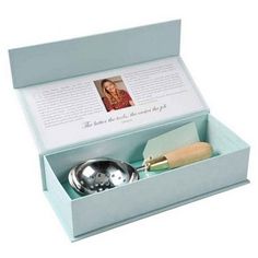 an open box with a metal bowl and brush in it on a white table top