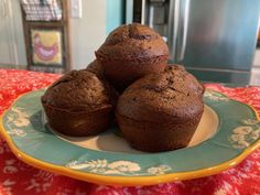 three chocolate muffins are on a plate