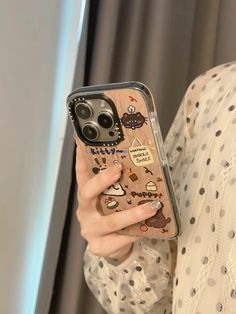 a woman is holding up her phone case with stickers on it and looking at the camera