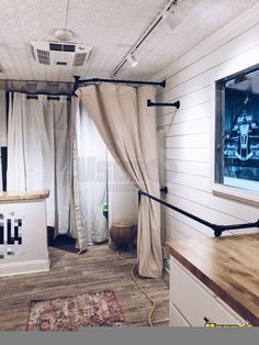 the inside of a tiny home with white walls and wood flooring, curtains open to let in natural light