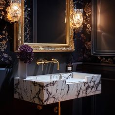 a bathroom sink with a marble counter top and gold trimmings on the wall