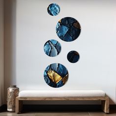 three circular mirrors hanging on the wall above a bench in front of a white wall