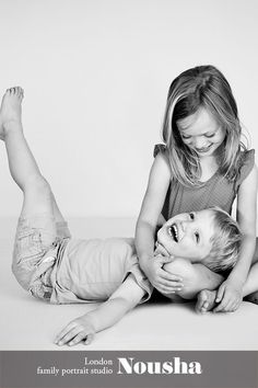 two young children playing with each other on the floor in black and white photo studio