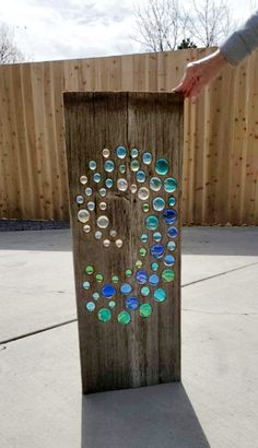 a person holding onto a wooden board with glass buttons on it and the word love painted on it