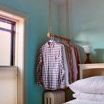 a bedroom with blue walls and clothes hanging on the rack in front of the bed