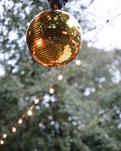 a disco ball hanging from a string in front of trees