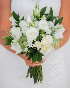 a bride holding a bouquet of white flowers