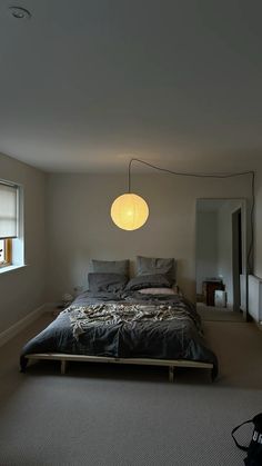 a bedroom with a large bed in the corner and a lamp hanging from the ceiling