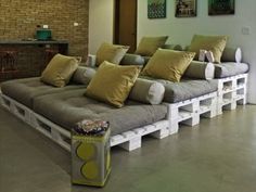 a couch made out of pallets with yellow pillows on it in a living room