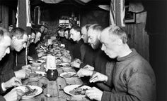 a group of men sitting around a table eating food