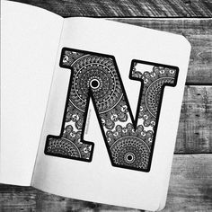 the letter n is made up of paisley patterns on a notebook with an open page