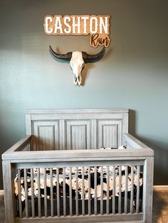 a baby crib in front of a wall with a cow skull mounted on it