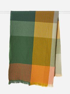 an orange, green and yellow checkered blanket hanging on a clothes line with white background