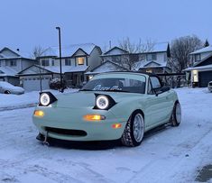 a green sports car is parked in the snow