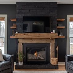 a living room with two black leather chairs and a television on the fireplace mantel