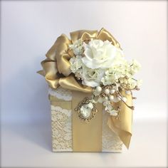 a bouquet of white flowers in a gift box with gold ribbon and bow on top