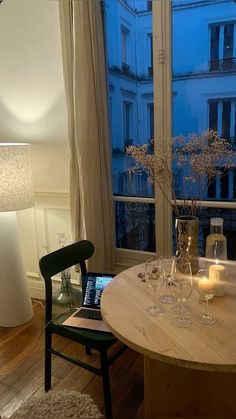 a table with two wine glasses and candles on it in front of a large window