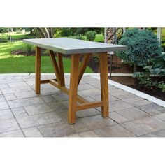 a wooden table sitting on top of a stone floor next to a lush green field