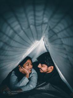 a couple cuddling under an umbrella in the dark with their arms around each other