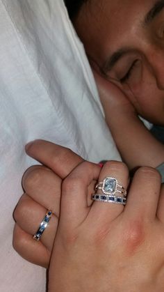 a man and woman are cuddling with each other while holding their wedding rings on their fingers