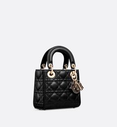 The Lady Dior bag epitomizes the House's vision of elegance and beauty. Sleek and refined, the timeless style is crafted in black lambskin with Cannage stitching, creating the unmistakable quilted texture. Brown tortoiseshell-effect resin D.I.O.R. charms complement the new removable chain strap with alternating pale gold-finish metal and brown tortoiseshell-effect resin O-links. The miniature Lady Dior bag can be carried by hand or worn crossbody as an ideal evening companion.. Lady Dior Bag Black, Dior Mini Bag, Lady Dior Mini, Mini Lady Dior, Icon Shoes, Backpack Tote Bag, Fashion Jewelry Earrings, Boot Pumps, Beach Accessories