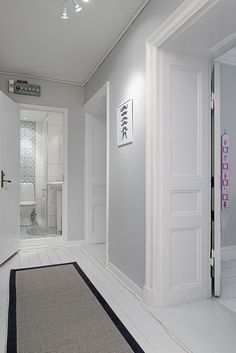 an empty bathroom with white walls and black trim on the door, along with a gray rug