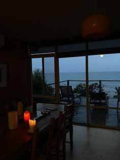 a table with two candles on it in front of an open window overlooking the ocean