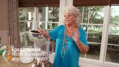 a woman standing in front of a blender filled with food