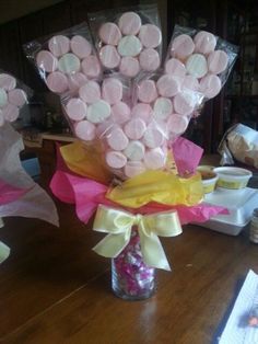 a vase filled with candy covered in pink and white candies on top of a wooden table