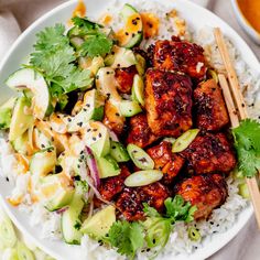 a white plate topped with meat and vegetables next to chopsticks on top of rice