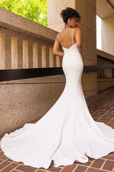 a woman in a white wedding dress is standing on the stairs looking at her back