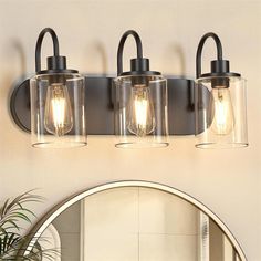 three light bathroom fixture with clear glass and black metal finish, on a white wall