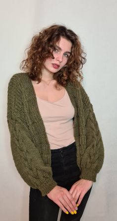 a woman with curly hair wearing a green cardigan