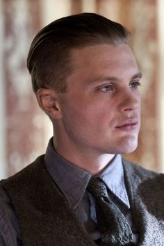 a young man in a vest and tie looking off into the distance with his eyes closed